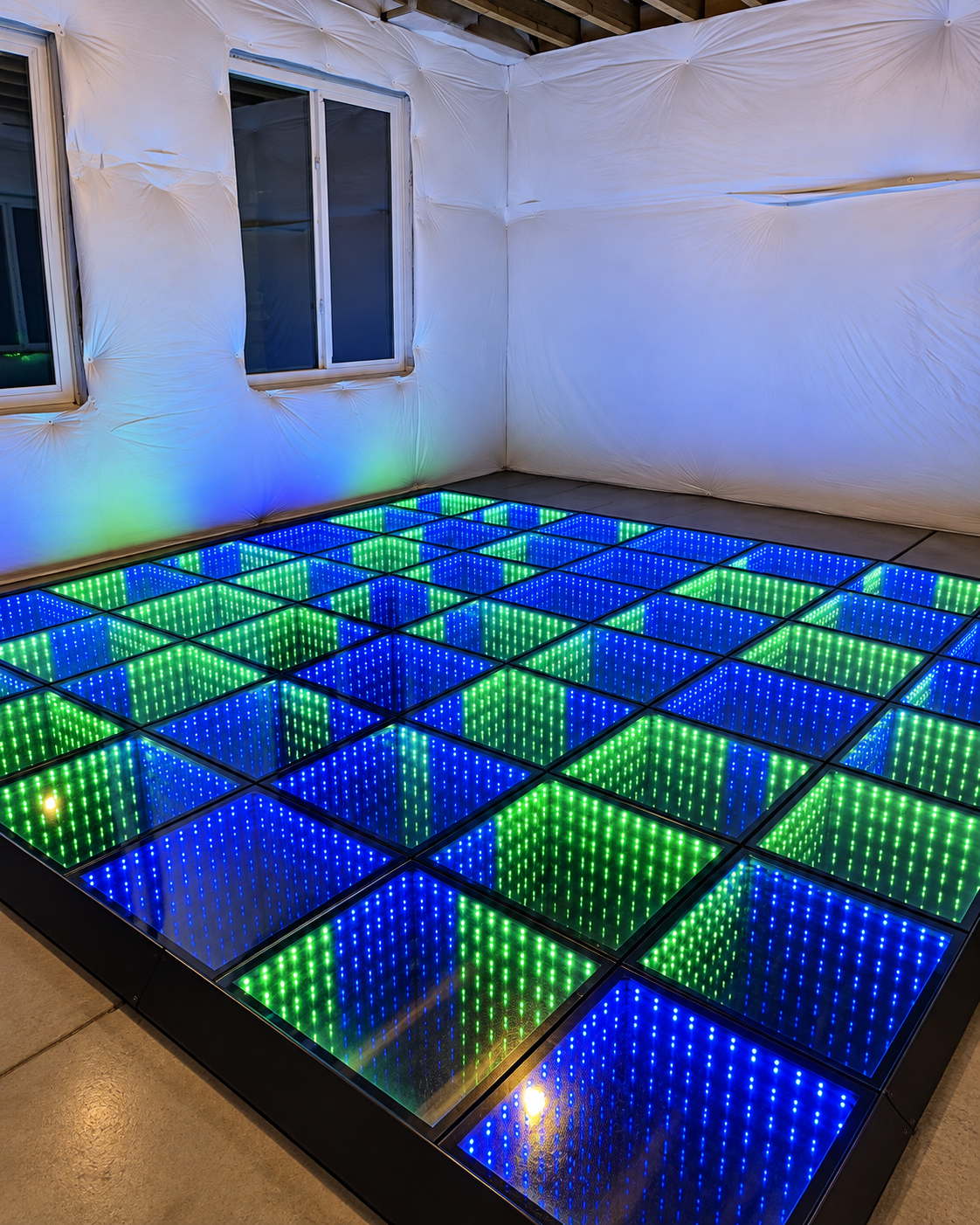 7 by 16 foot LED infinity dance floor glowing blue and green in an indoor room